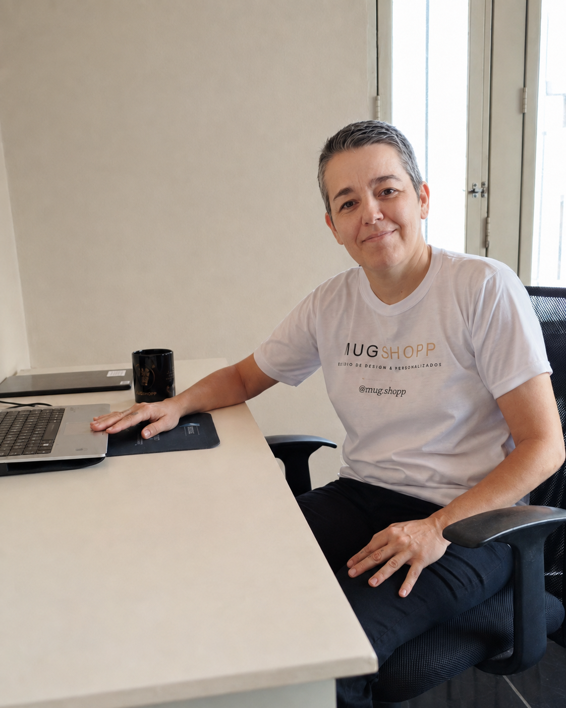 Luciana Pereira, fundadora da MugShopp, sentada ao notebook no ateliê